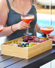 Person holding a glass of red cocktail with a charcuterie board on a table